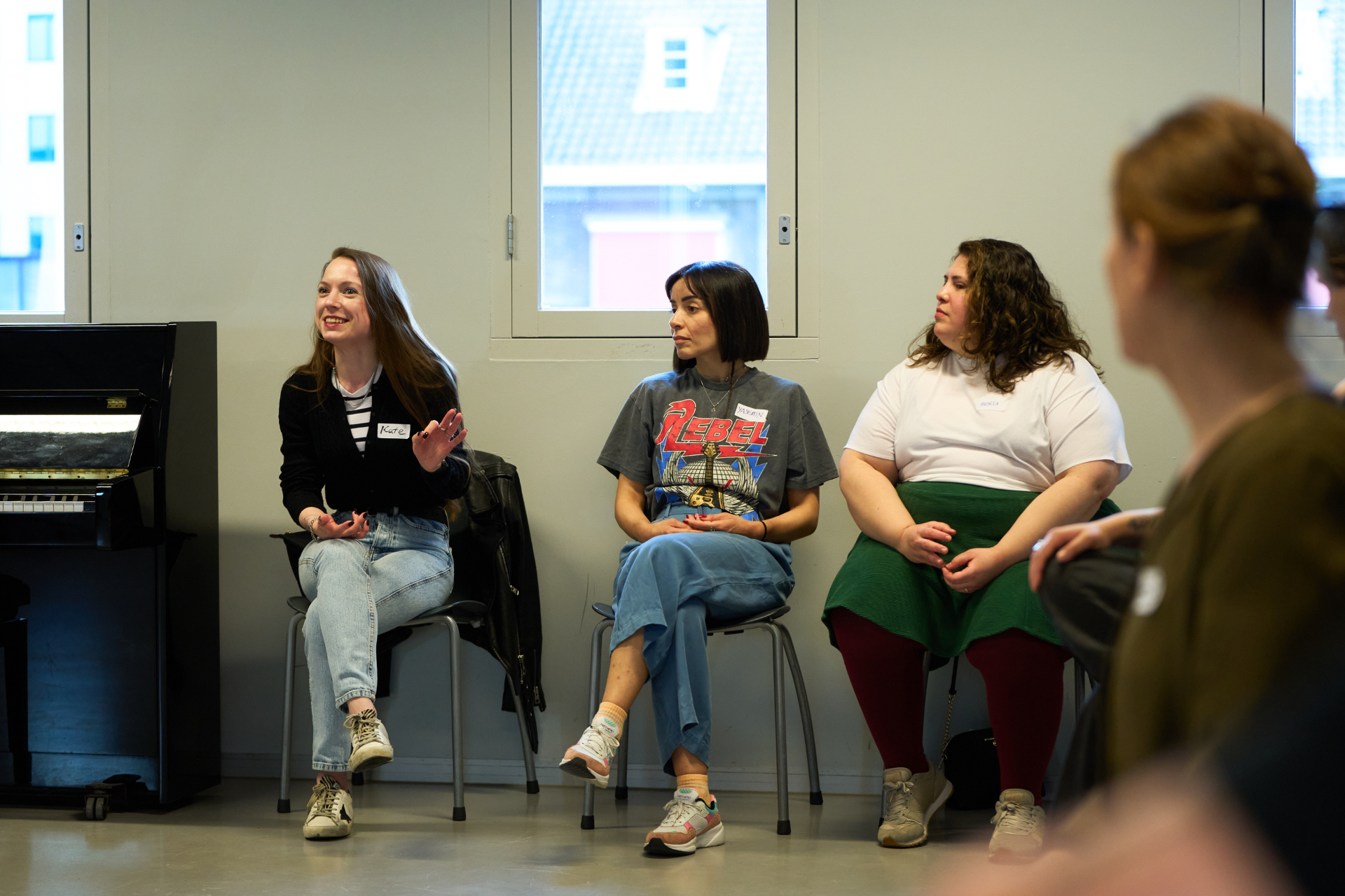 Three participants seated together during a Monnarc workshop, one mid gesture while the others listen.